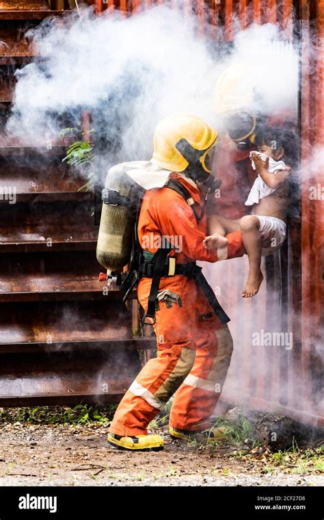 Firefighter rescue girl little child from burning building. He hold the ...