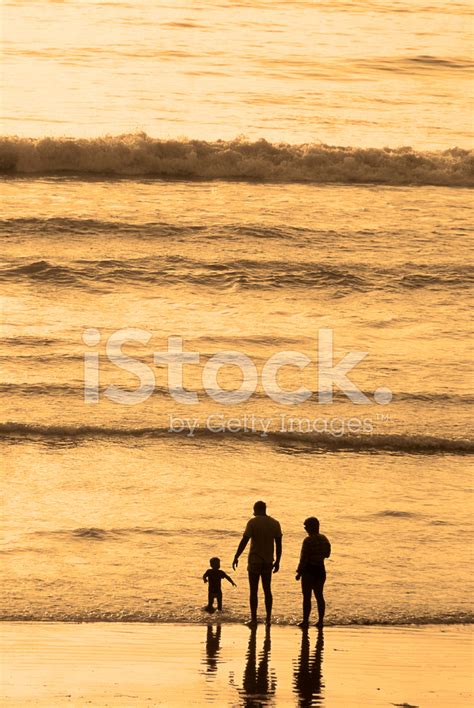 Young Family Walking On Beach At Sunset Stock Photo | Royalty-Free ...