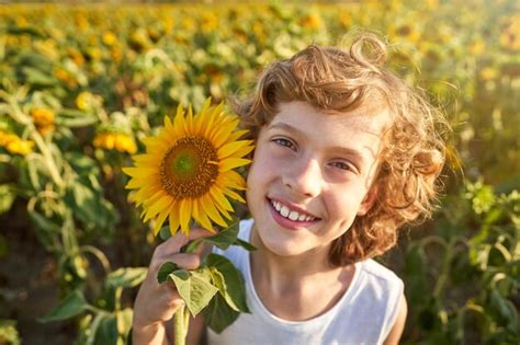 Premium Photo | Cheerful boy with sunflower growing in field on sunny day