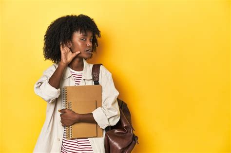 Premium Photo | Studious teen girl with backpack and notebooks yellow backdrop trying to ...