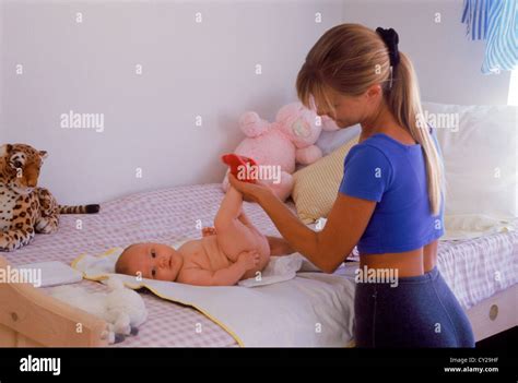 Mother changing babies diaper at home on bed Stock Photo - Alamy