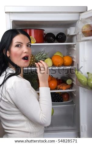 Woman with open full fridge with fruits and vegetables taking a berry grape in her mouth - Stock ...