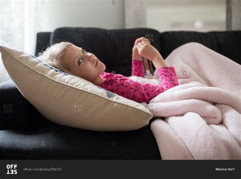 A young girl lying down on a couch stock photo - OFFSET