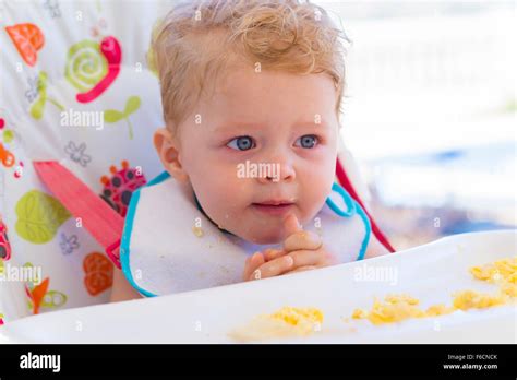 Gorgeous happy toddler eating food in high chair Stock Photo - Alamy