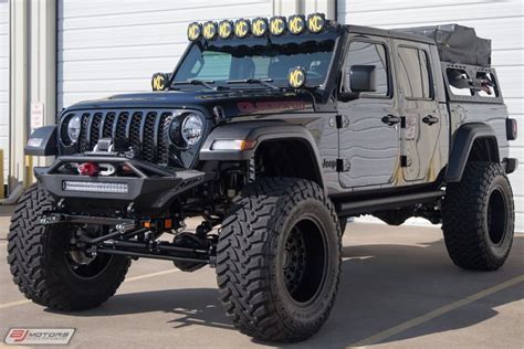 a black jeep with lights on it parked in front of a building