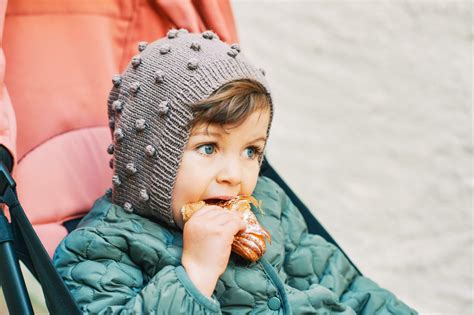 Toddler sitting in stroller and eating croissant, pastry snack 34868536 Stock Photo at Vecteezy