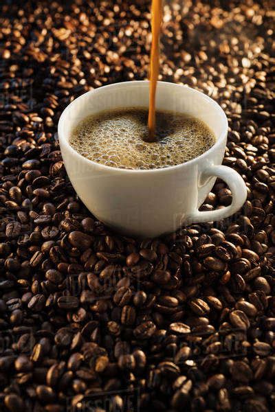 Pouring coffee into cup on coffee beans, studio shot - Stock Photo ...