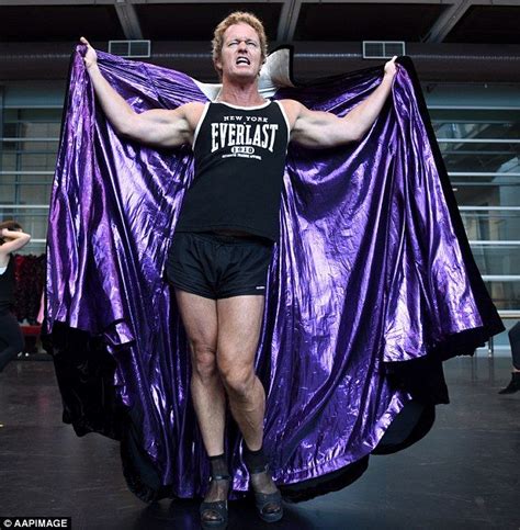 a man in black shirt and shorts holding purple cloth over his shoulders ...