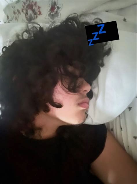 a woman with curly hair laying in bed