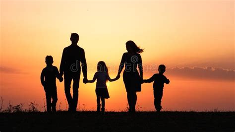 Silhouettes of Happy Family Holding the Hands in the Meadow during Sunset. Stock Image - Image ...