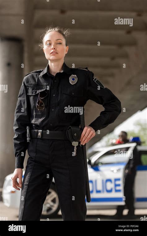 attractive female police officer in uniform looking at camera with ...