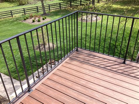 a wooden deck with black iron railings and green grass in the backround