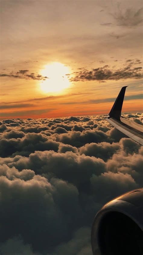 an airplane wing flying above the clouds at sunset