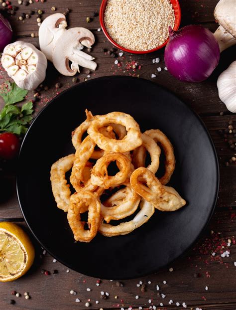 Tasty calamari rings on plate surrounded with aromatic seasonings ...