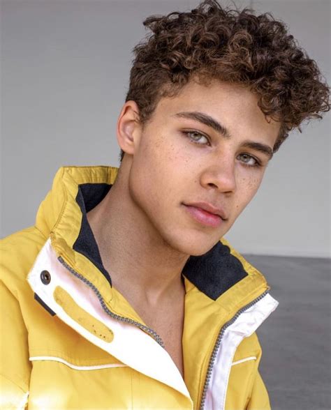 a young man with curly hair wearing a yellow jacket