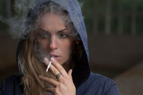 Royalty-Free photo: Woman wearing blue hooded jacket while puffing a single cigarette | PickPik