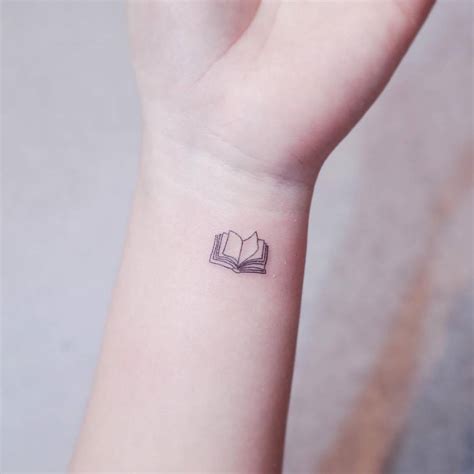 Tiny fine line book tattoo on the wrist.