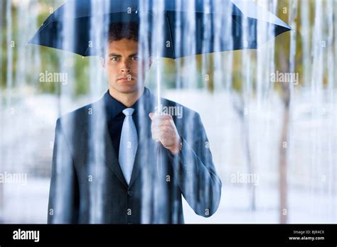 Businessman holding umbrella in rain Stock Photo - Alamy