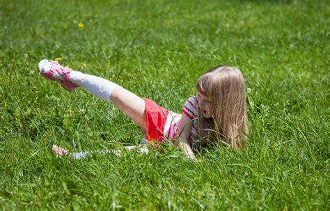 Little girl lying on grass stock image. Image of merriment - 68324177