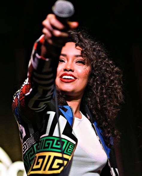 a woman holding a microphone up to her face with one hand and another arm in the air
