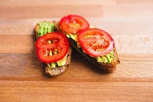 Healthy vegetable snack made of halved avocado and small tomatoes ...