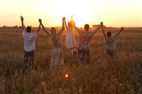 Premium Photo | Family holding hands looking at sunset in field