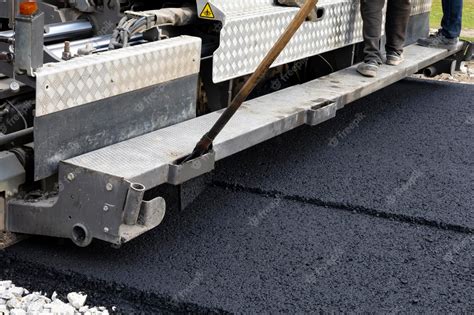 Premium Photo | Worker operating asphalt paver machine during road ...