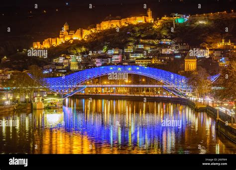 Tbilisi Old Town with the illuminated Europe Bridge reflecting in Kura ...