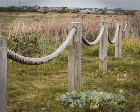 a row of wooden posts with rope wrapped around them in a grassy area ...