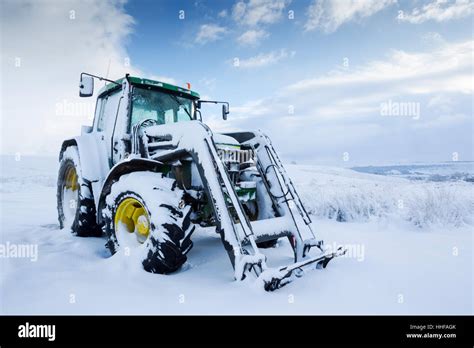 Snow covered green tractor with yellow wheel hubs in North York Moors ...