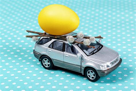 Grey toy car with a yellow egg and willow branches on a blue background - Creative Commons Bilder