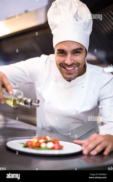 Handsome chef pouring olive oil on meal Stock Photo - Alamy