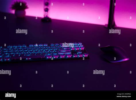 Low light scene of computer input devices, pink illuminated wall in background. Professional ...