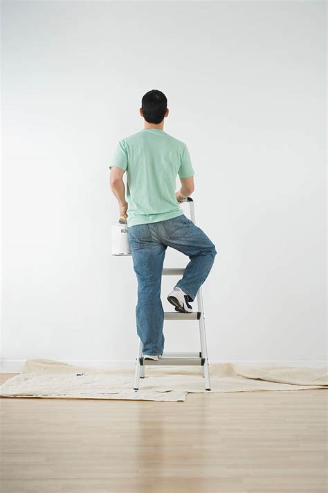 Man climbing a ladder with paint can to paint a wall - StockFreedom - Premium Stock Photography