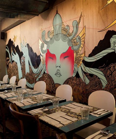 a dining room with tables and chairs in front of a mural on the wall behind them