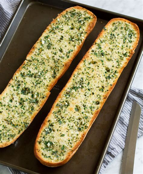 Two garlic bread halves on a dark baking sheet. Shown after toasting. | Receta de pan de ajo ...