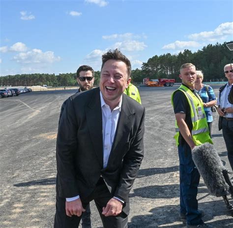 a man in a suit and tie standing next to a microphone on an airport tarmac