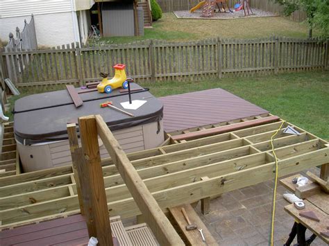 an outdoor hot tub being built in a backyard with wooden decking and fence around it