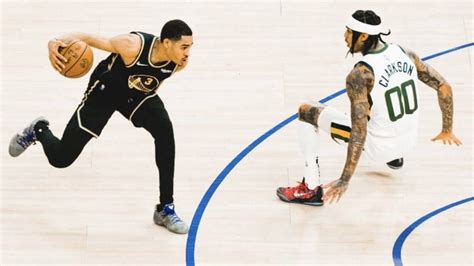 two men playing basketball on a court with one holding a ball and the other running