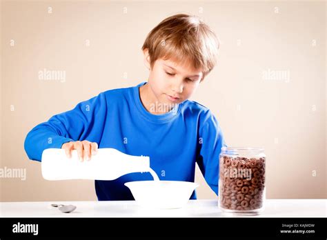 Kid eating breakfast. Boy pouring milk into a bowl of cereal Stock Photo - Alamy