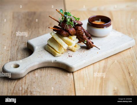 Anticucho Beef skewers with Yuka fries and tari sauce are shown on a table in a restaurant Stock ...