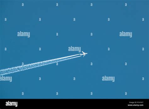 Airplane leaving vapor trail in blue sky Stock Photo - Alamy