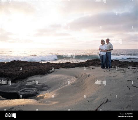 Couple holding each other on beach at sunset Stock Photo - Alamy