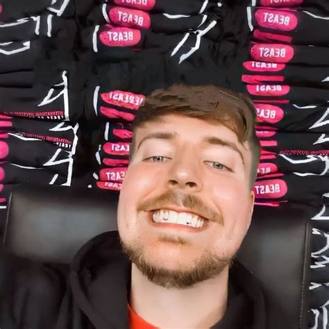 a man sitting in front of a pile of black and pink shirts with the ...