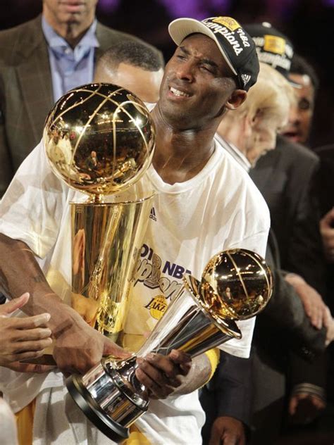 the basketball player is holding two trophies in his hands