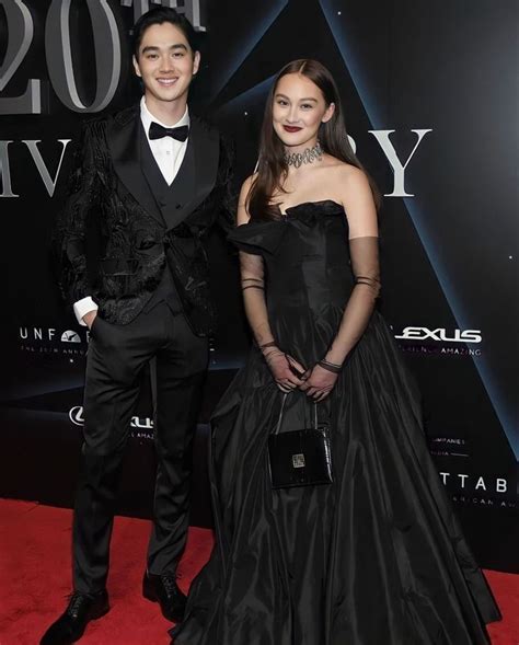 two people standing on a red carpet in formal wear