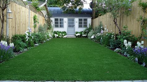 Artificial easy grass lawn summer house sandstone paving and white flower planting scheme London ...