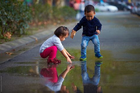 "Two Kids Playing The Water In The Road After Rain" by Stocksy ...