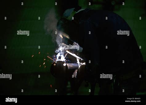 Construction worker welding pipe in a fabricating plant while wearing ...