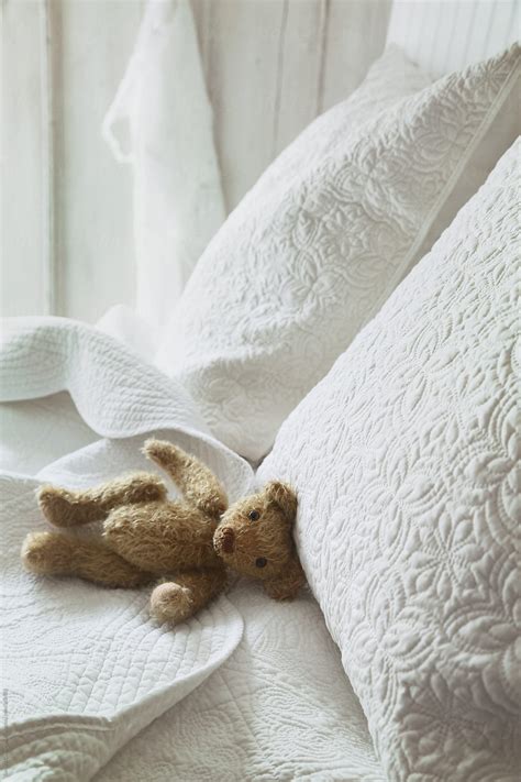 Small teddy bear on bed by Sandra Cunningham - Stocksy United